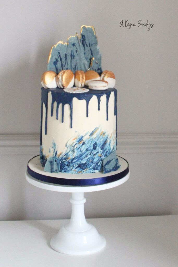 A white and navy chocolate drip cake with navy drip, ideal for a birthday cake