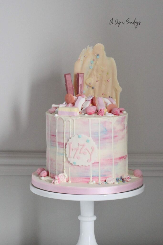 A pink and white chocolate drip birthday cake