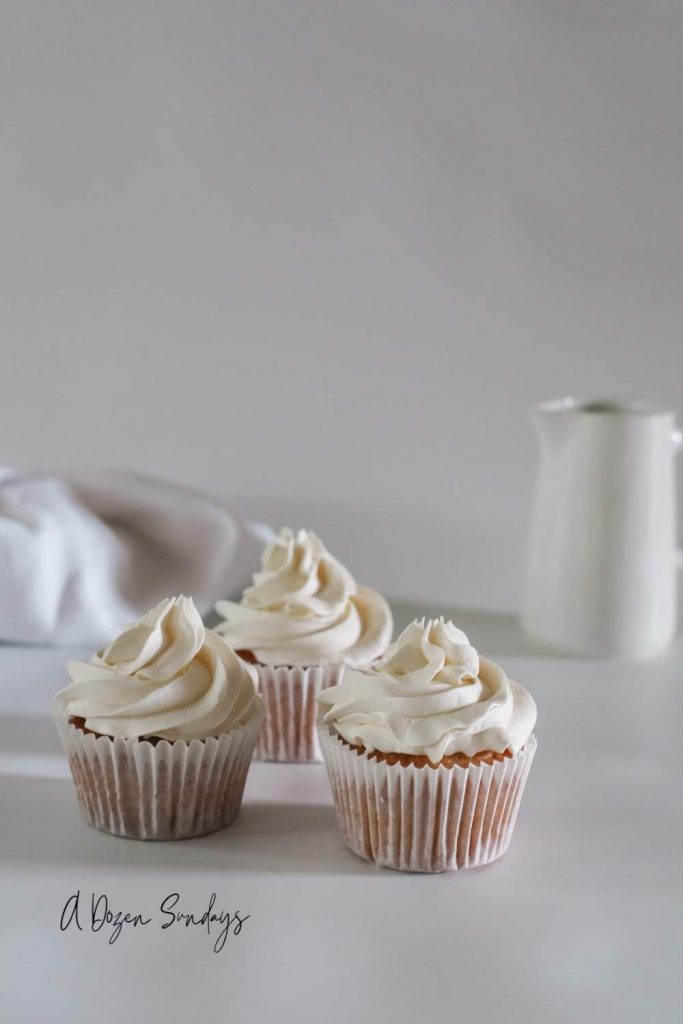 Easy Vanilla Cupcake Recipe - Vanilla Cupcake in White Wrapper with White Buttercream - A Dozen Sundays
