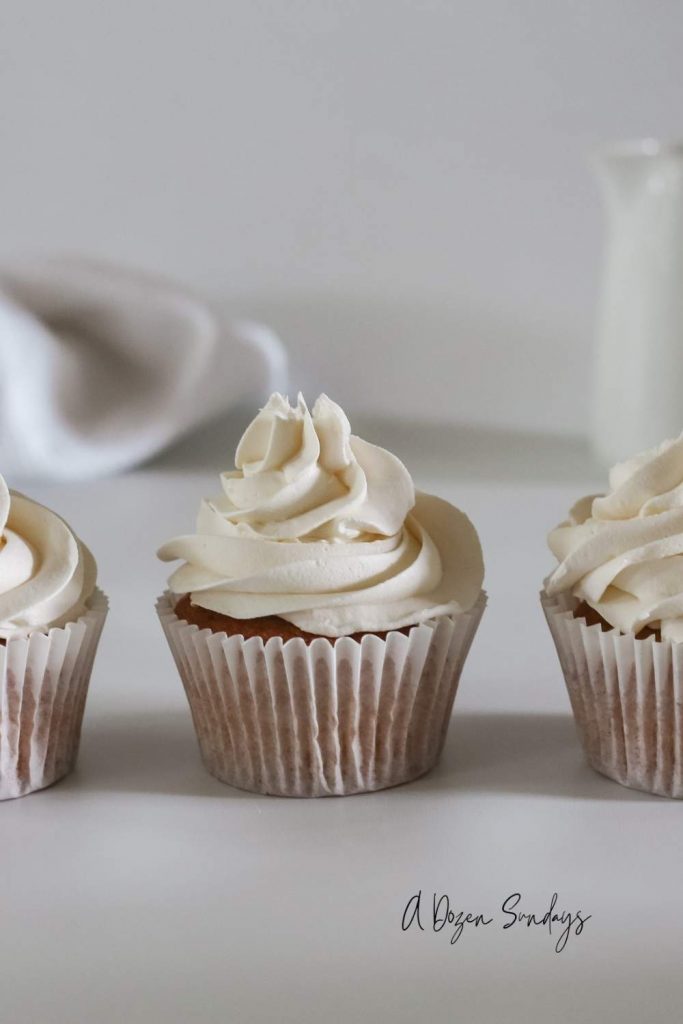 Easy Vanilla Cupcake Recipe - Vanilla Cupcake in White Wrapper with White Buttercream - A Dozen Sundays