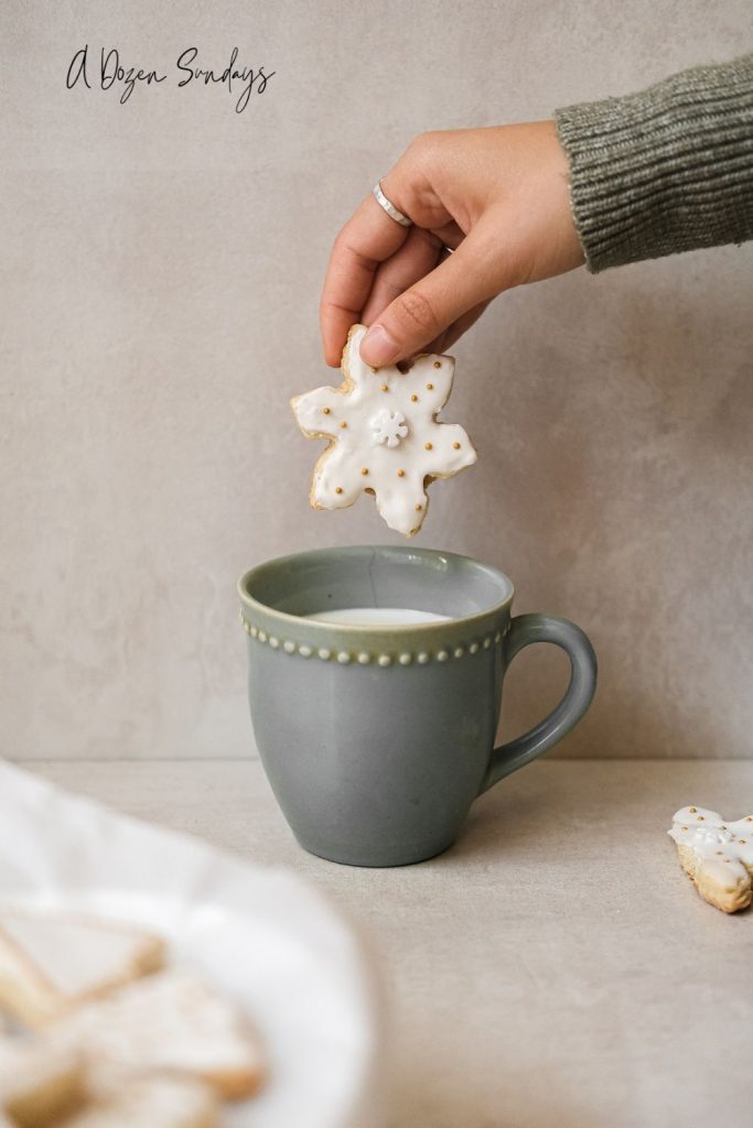 A hand holding a snowflake shaped Christmas cookie