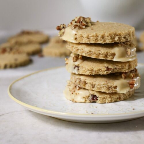 Pumpkin Spice Pecan Shortbread Cookies With Maple Glaze stacked up on a plate
