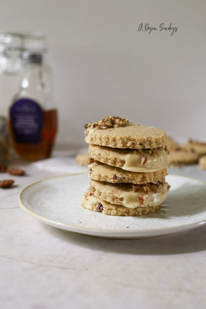 Pumpkin Spice Pecan Shortbread Cookies With Maple Glaze stacked up on a plate